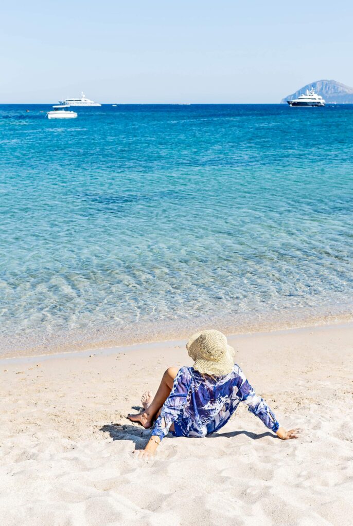 A women in a women had sitting in the sand by the sea