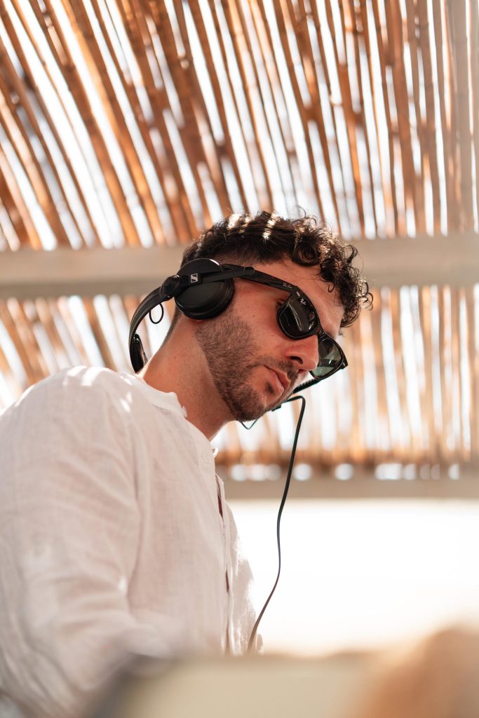 A man wearing sunglasses and wired over-head headphones