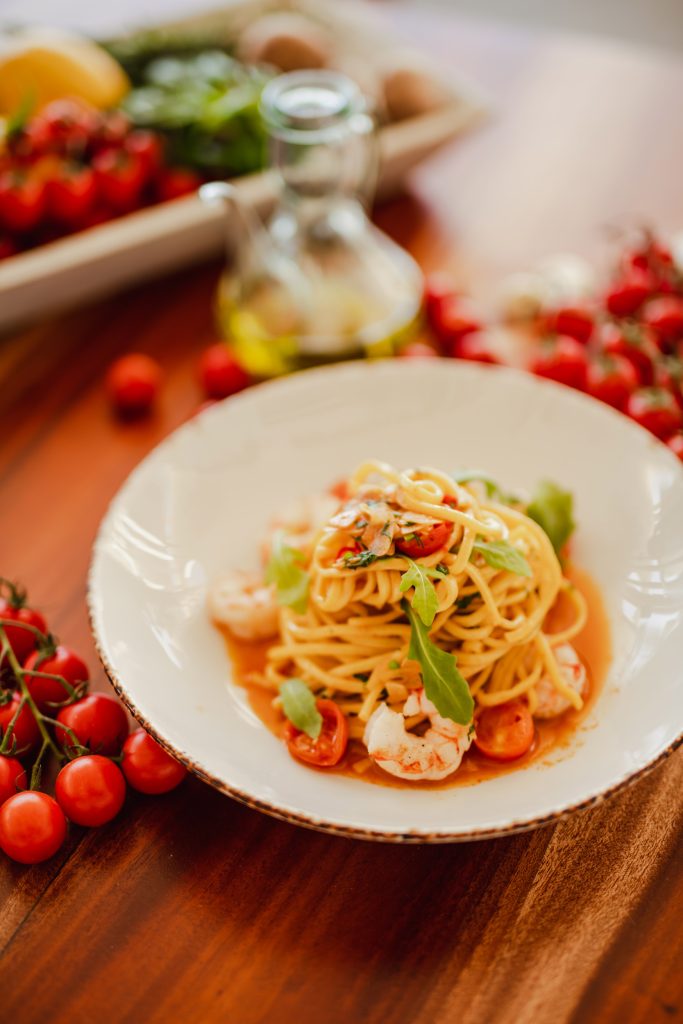 photo of a plate of pasta on a table with blurred out ingredients in the background