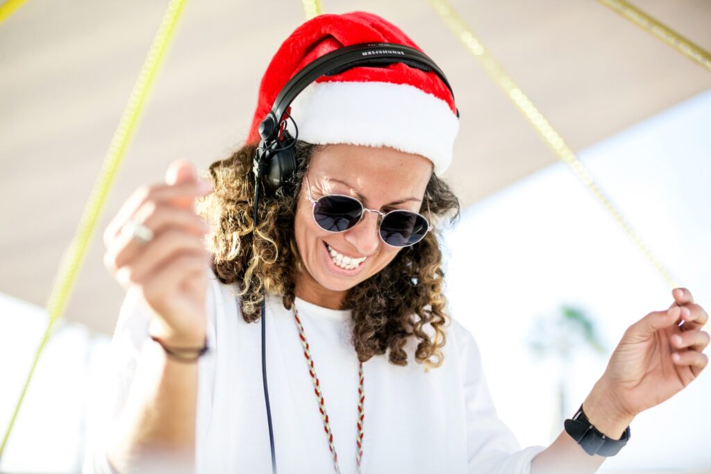 A DJ in a festive Santa hat and headphones, enjoying the vibrant atmosphere of a Christmas celebration at the beach