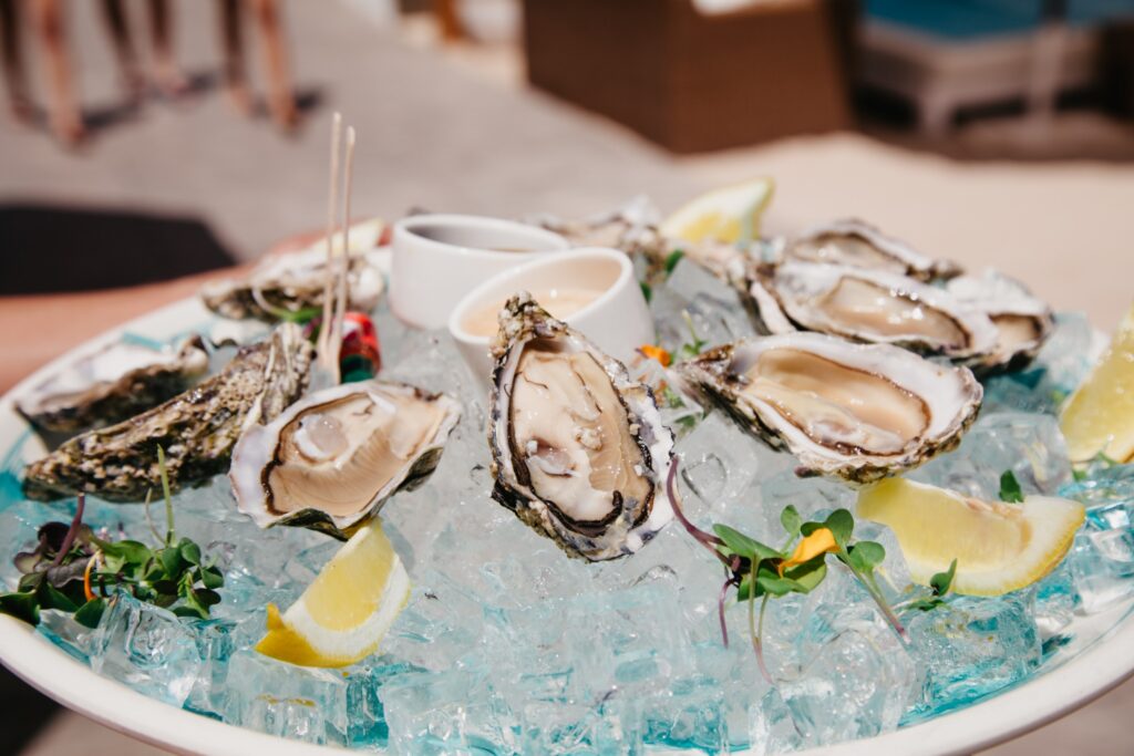 Fresh oysters on a bed of ice, set against a picturesque beach backdrop, perfect for a festive brunch celebration