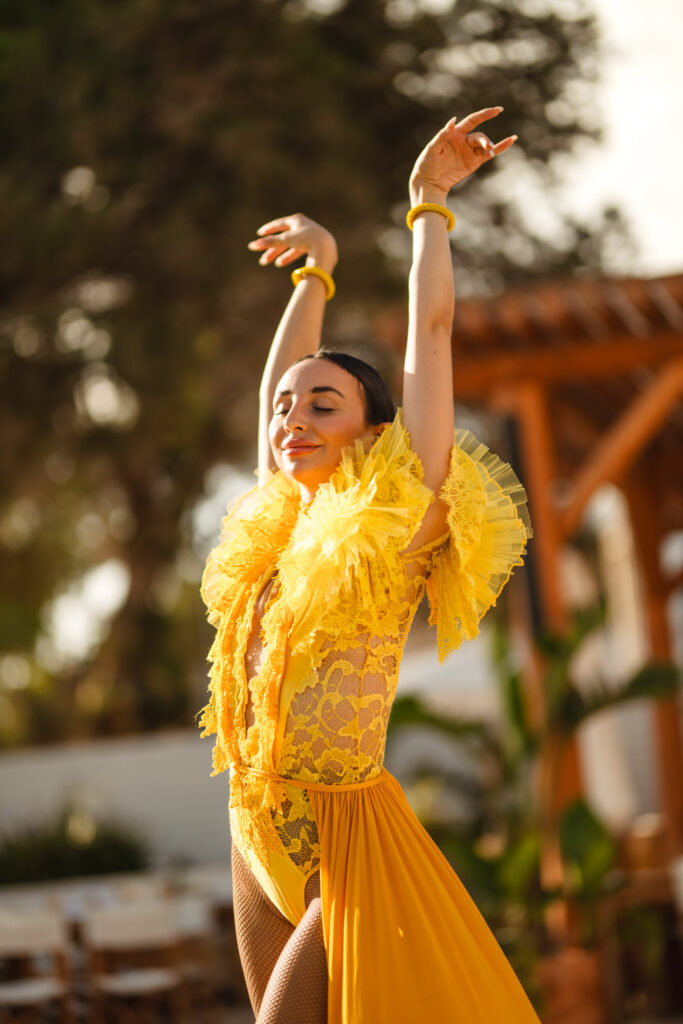 A women in a bright yellow decorative outfit, dancing with are positioned in the air