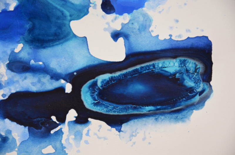 Blue ink droplets spreading across paper