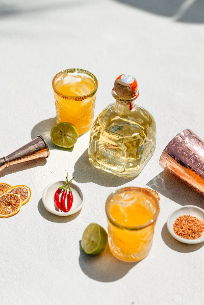 Cocktails in a salted rim glass next to a bottle of Patron