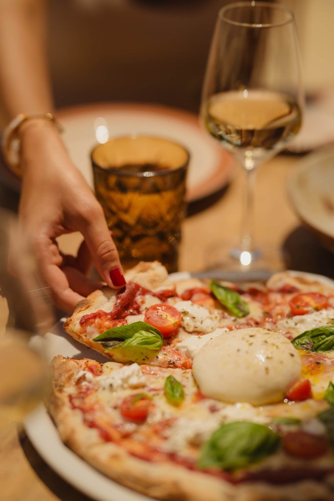 A lady taking a slice of margherita pizza