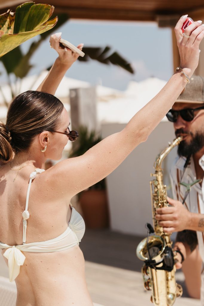 Lady dancing with her hands in the air in front of a saxophone player