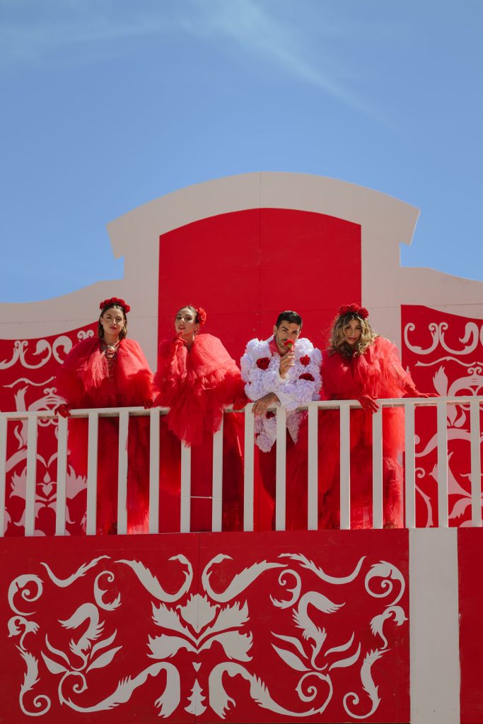 A group of individuals standing on a red balcony wearing matching red and white outfits