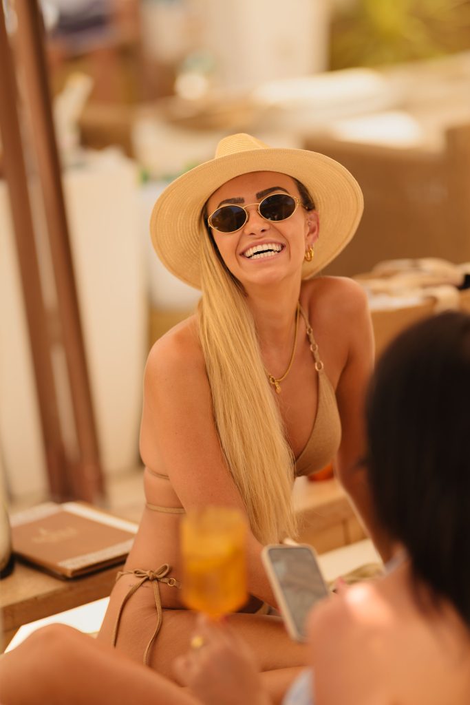 lady wearing sunglasses and sun hat, smiling at the camera