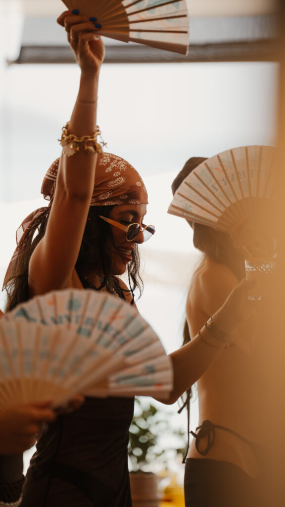 Women wearing a bandanna, holding an open fan in the air