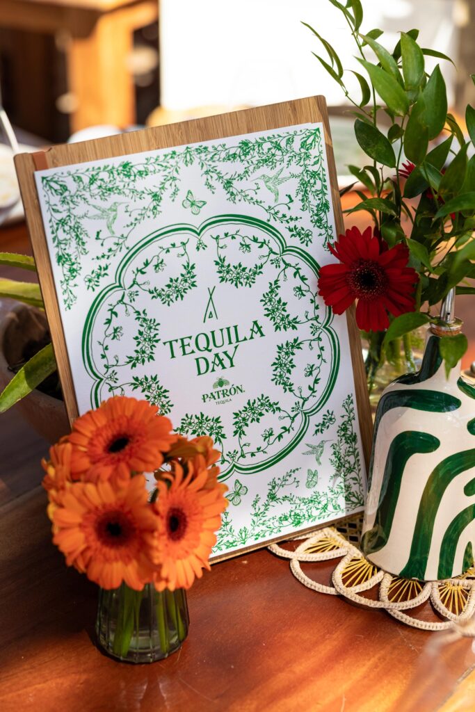 A nikki Beach poster stating "tequila day" next to a vase of small flowers