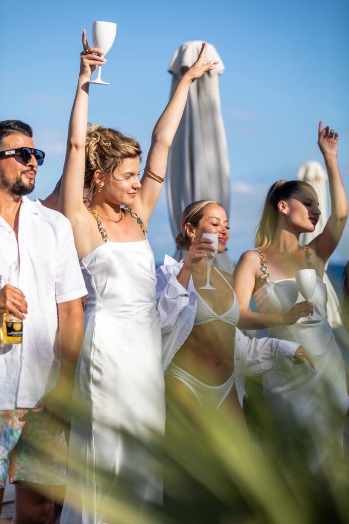 Guests in white attire joyfully toast with glasses, embodying the vibrant spirit of Saturdance at Nikki Beach Santorini