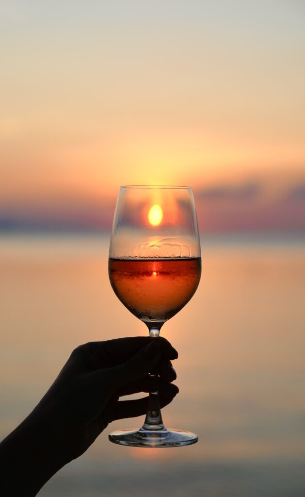 A guest enjoys a glass of wine, silhouetted against a breathtaking Santorini sunset, capturing the essence of summer festivities